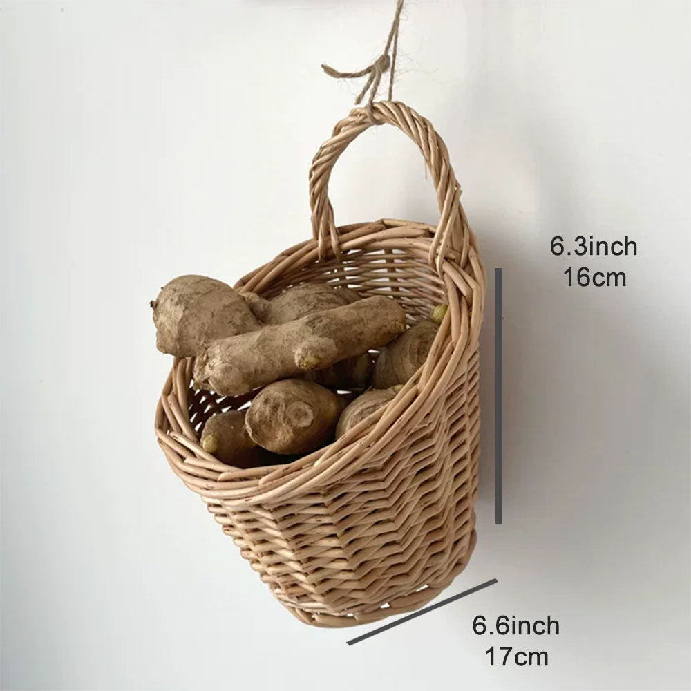 A woven hanging basket made of natural light brown wicker, shown with a hanging loop and filled with root vegetables. 