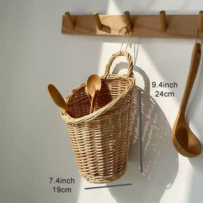 A woven natural wicker basket hanging from a wooden peg rack on a white wall, containing wooden spoons. Text overlays show the basket's dimensions: 9.