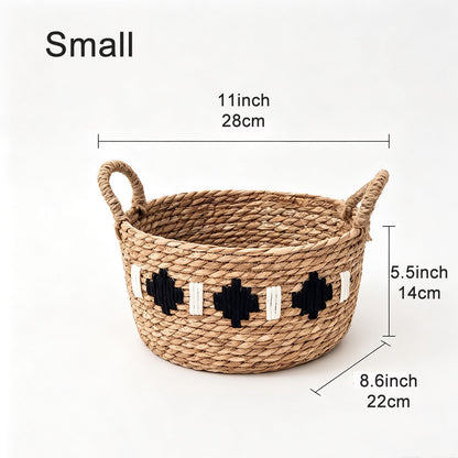 A woven natural-fiber basket with two loop handles and black-and-white geometric accents