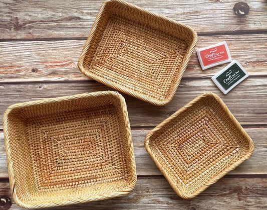 Set of three rectangular rattan baskets in various sizes, with the smallest containing a white coffee mug molded with the word 'coffee', placed on a wooden surface.